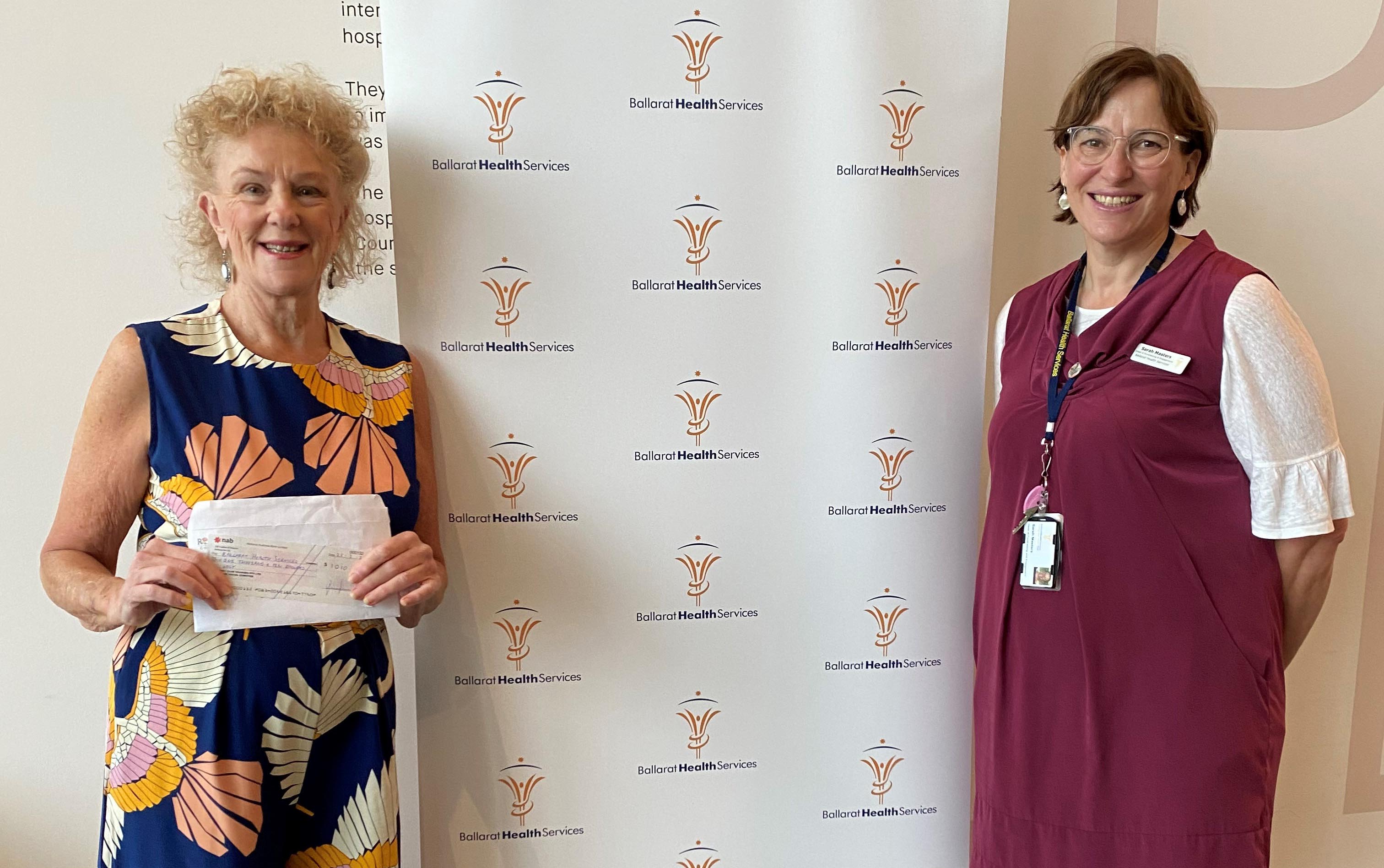 Head of Fundraising & Engagement Sarah Masters accepting a cheque from Helen Harris, Rosebank Village event organiser and resident.
